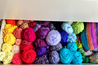 an open drawer full of balls of yarn, from yellow through to green following the rainbow order with multi-coloured yarn housed at the end