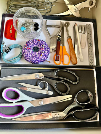 open drawer with two flat trays next to each other. Front tray holds different types of scissors and the back tray holds various small sewing tools
