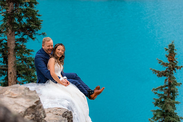 bride and groom kiss next to Moraine Lake turquoise blue color in Rocky Mountains