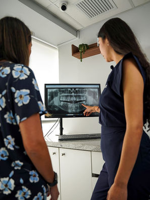 Two women review dental X-ray on screen in a modern dental office.