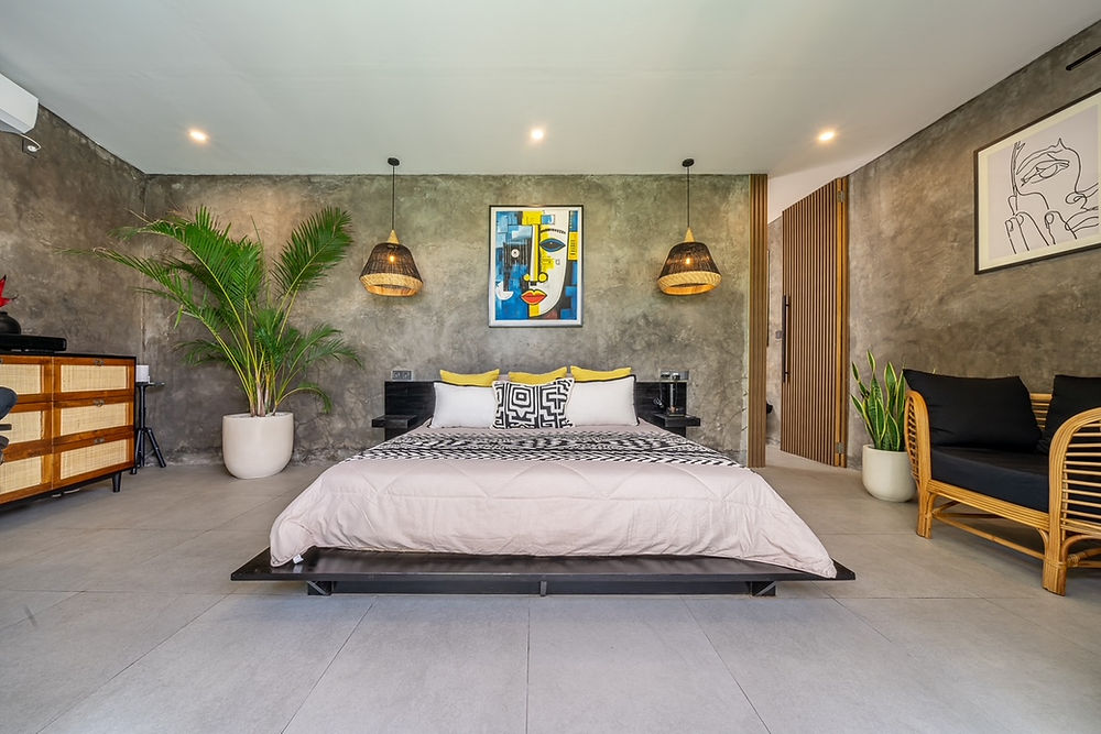 Modern bedroom with concrete walls, large bed, abstract art, and plants