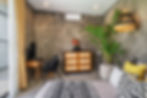 Contemporary bedroom with concrete wall, plant, and wooden dresser