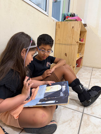Crianças lendo um livro juntas em momento de leitura compartilhada no ambiente preparado da escola Montessori no Tatuapé em São Paulo.
