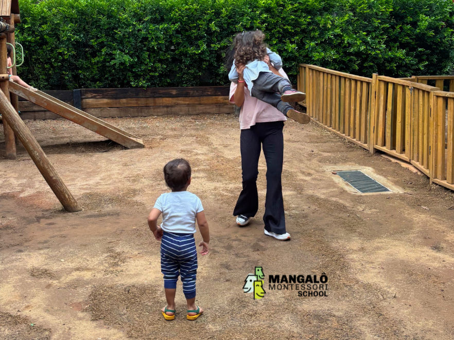 Professora da educação infantil em parque, recendo crianças em fase de adaptação e brincando com elas no parque