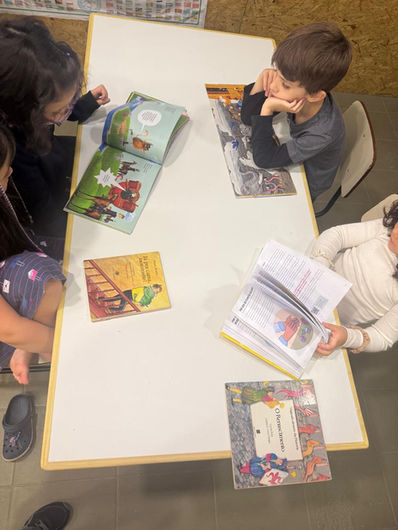 Crianças explorando livros e realizando leitura em mesa de estudo no ambiente preparado da escola Montessori no Tatuapé em São Paulo.