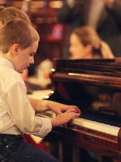 Učitelka vede chlapce při individuální výuce hry na klavír.