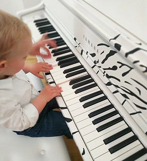 Dítě u bílého klavíru Yamaha během klavírního kroužku pro předškoláky v Praze – hravá forma výuky hudby.