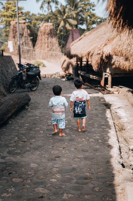 two Sumba boys walking down traditional village
