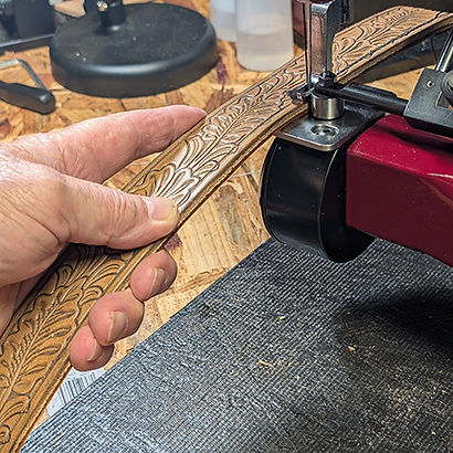 Artisan stitching a hand-tooled leather belt with a sewing machine in a workshop – RLR Leather craftsmanship process