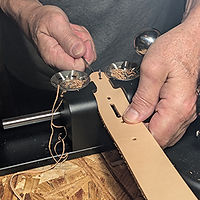 Artisan hand-stitching and shaping a natural leather belt using traditional tools on a wooden workbench – RLR Leather craftsmanship process