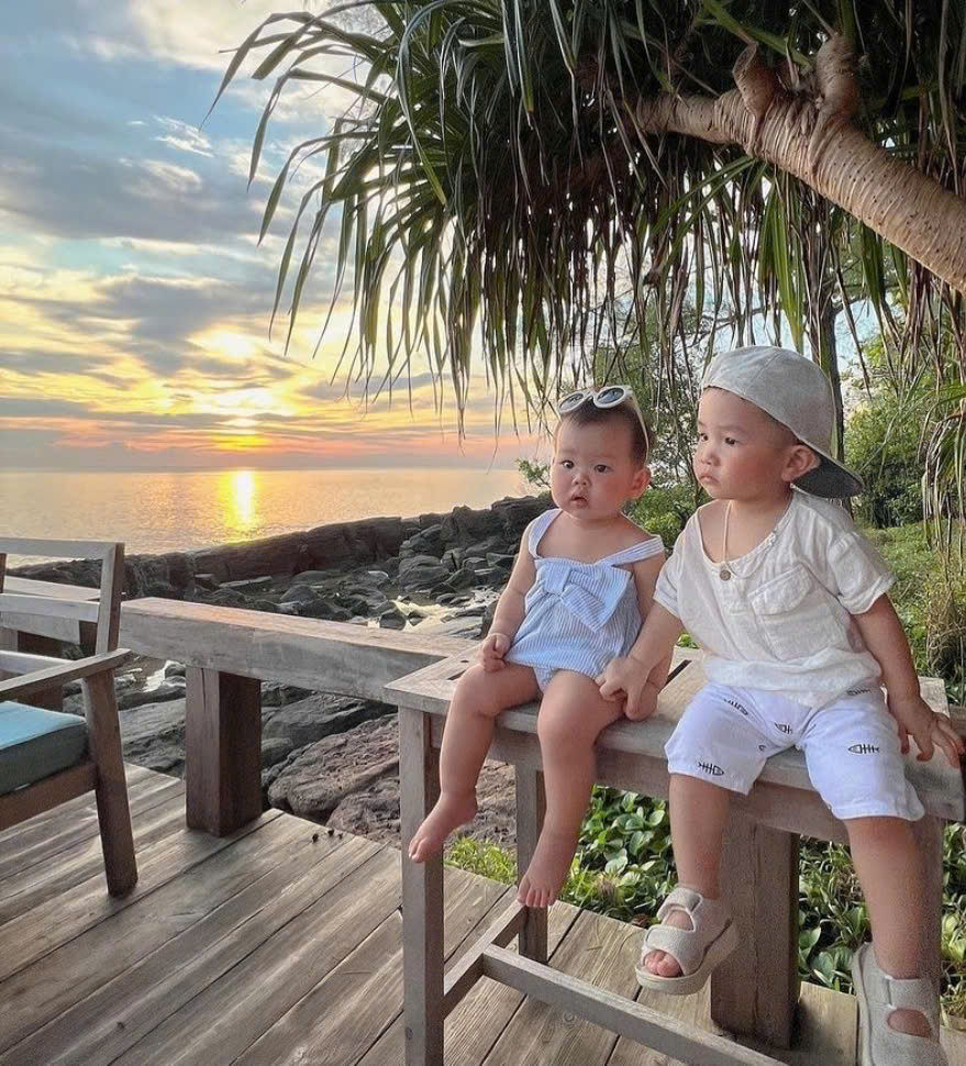 Family with baby and toddler enjoying sunset on a quiet Vietnam beach, warm evening light and calm sea