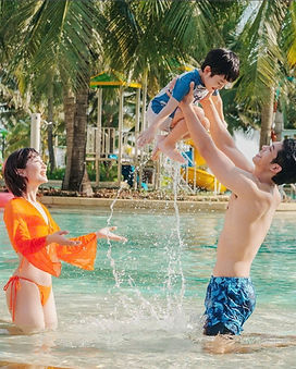 Parents relaxing with baby at An Bang Beach in Hoi An Vietnam on a family holiday