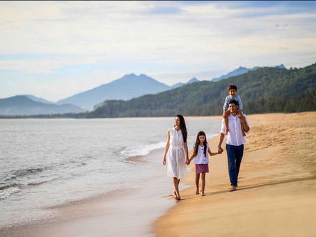 Family walking along a calm Phu Quoc beach at sunrise with a toddler and young child on white sand, turquoise Gulf of Thailand water
