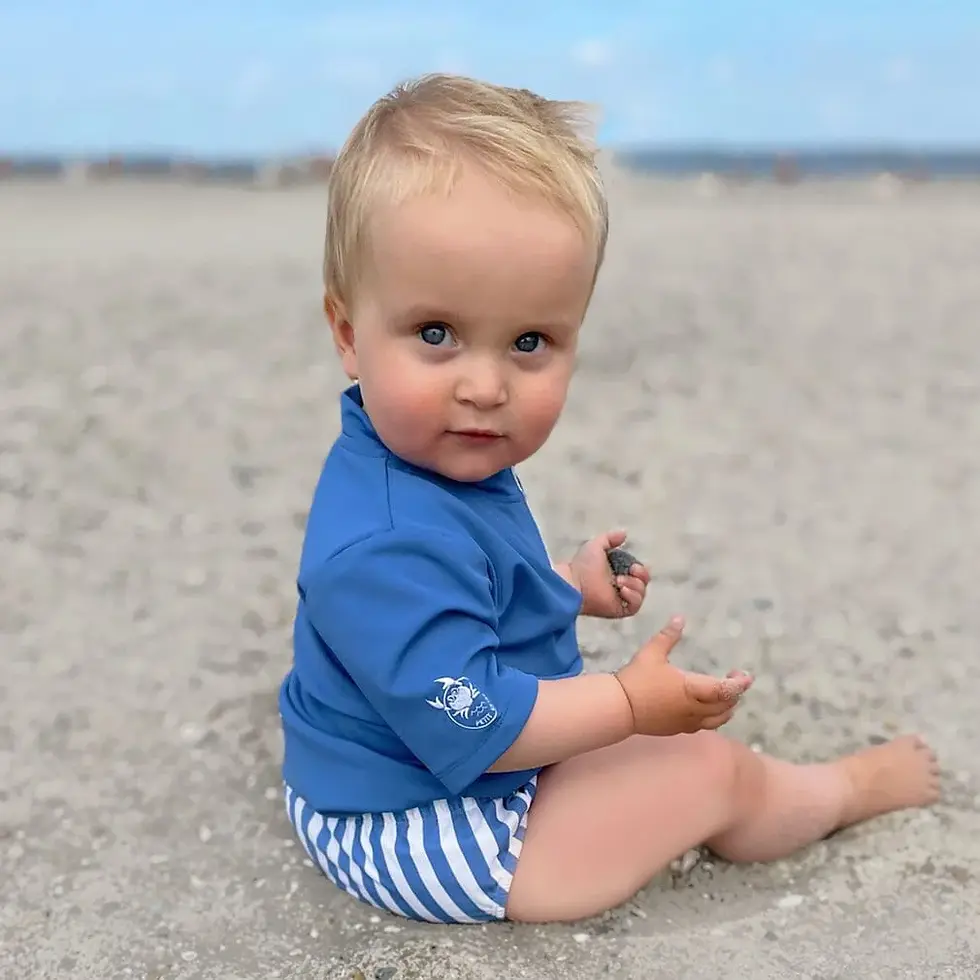 Toddler wearing a swimming diaper playing on a sandy beach in Vietnam