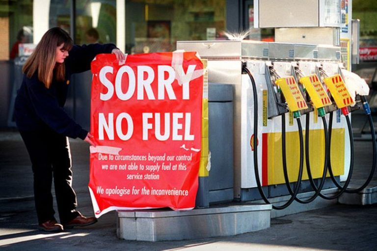 Woman putting up sign at petrol station during UK-wide shortage