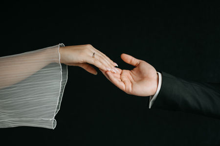 Elegantes Brautpaar reicht sich die Hand bei eleganter schwarz-weißer Hochzeit