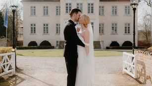 Elegantes Brautpaar küsst sich vor dem Gut Hasselburg