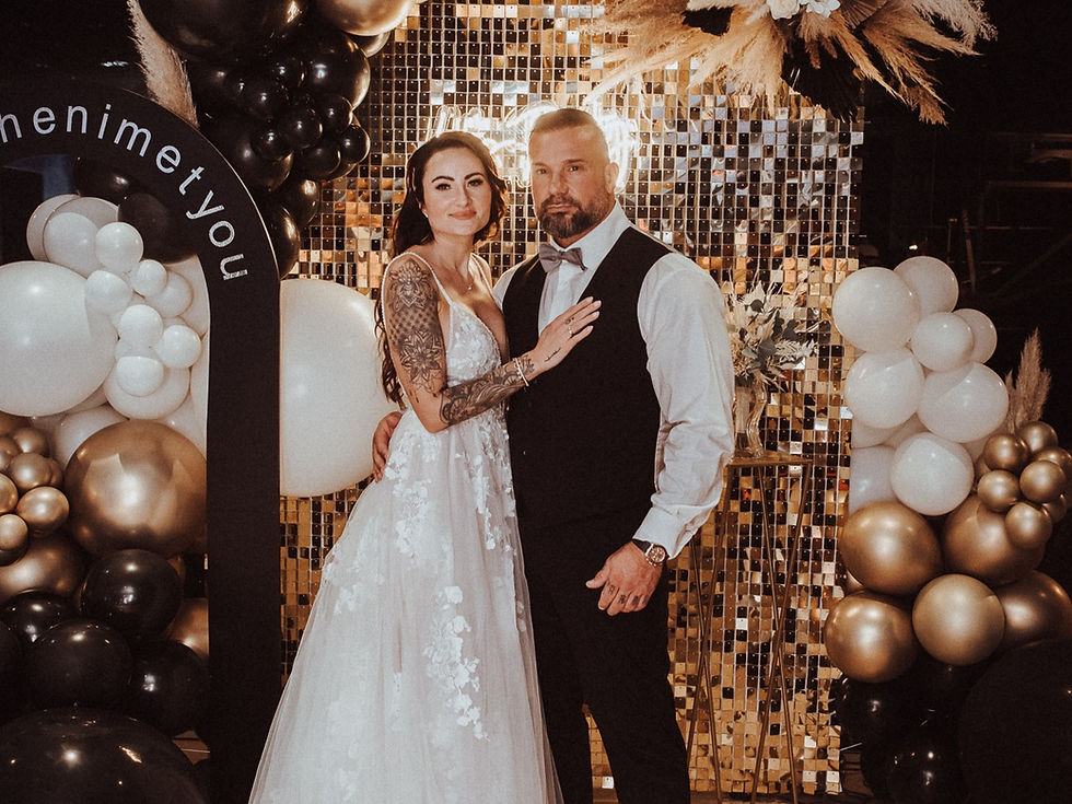 Modernes Brautpaar vor gold-schwarzem Backdrop mit Ballons