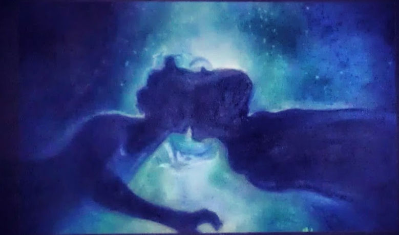 Silhouetted figures kissing against a cosmic backdrop with swirling blue and green hues, creating a dreamlike, romantic atmosphere.