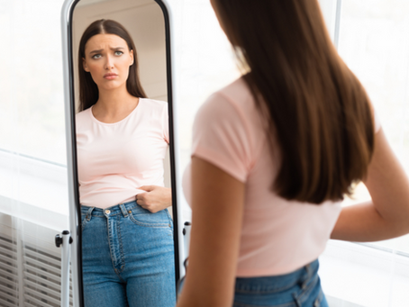 "Femme qui se juge dans le miroir, symbolisant le poids émotionnel, le mal-être corporel et les blocages inconscients liés à l’image de soi."