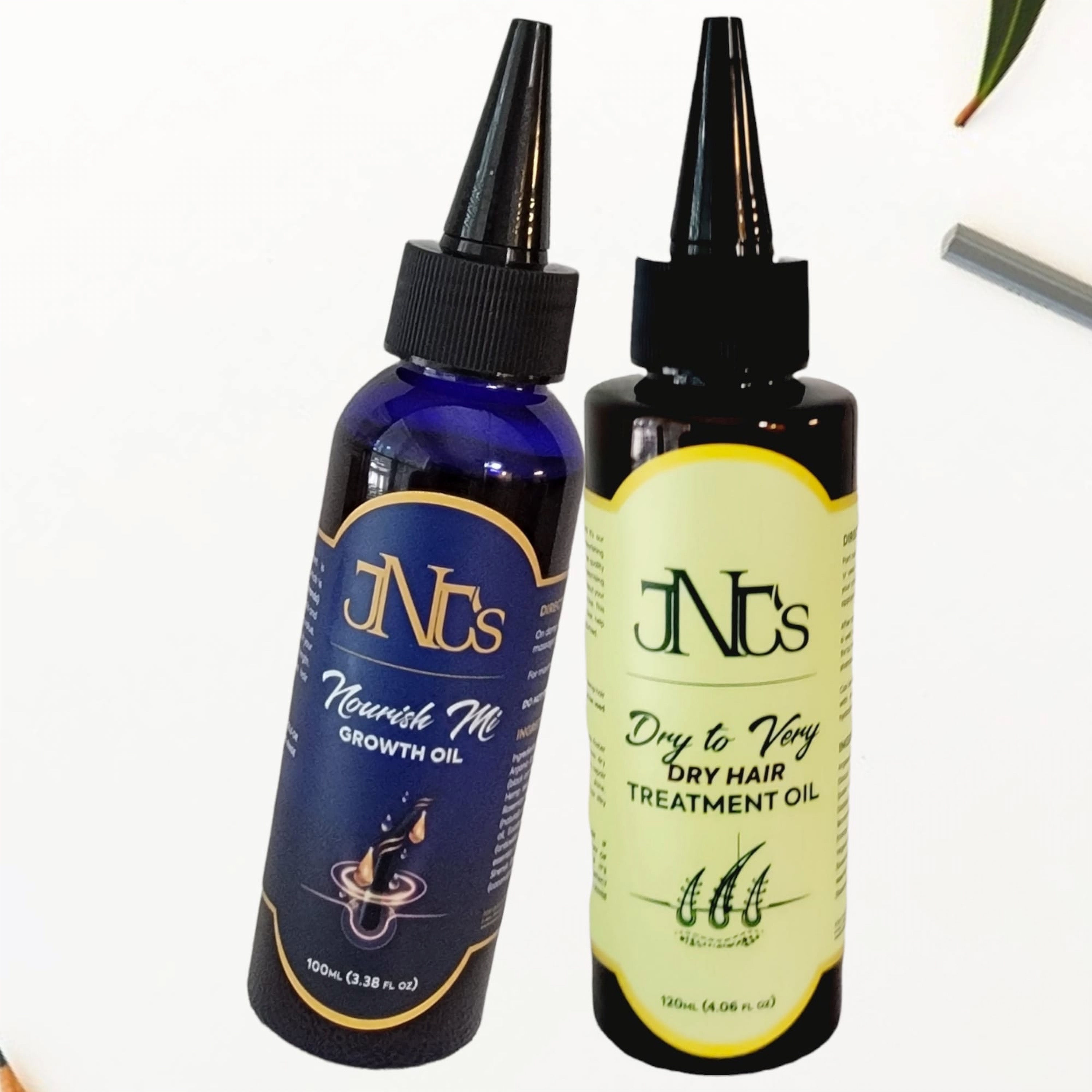 Dropper bottles of the JNJS's Nourish Mi Growth Oil and the JNJS's Dry & Very Dry Hair Treatment Oil.