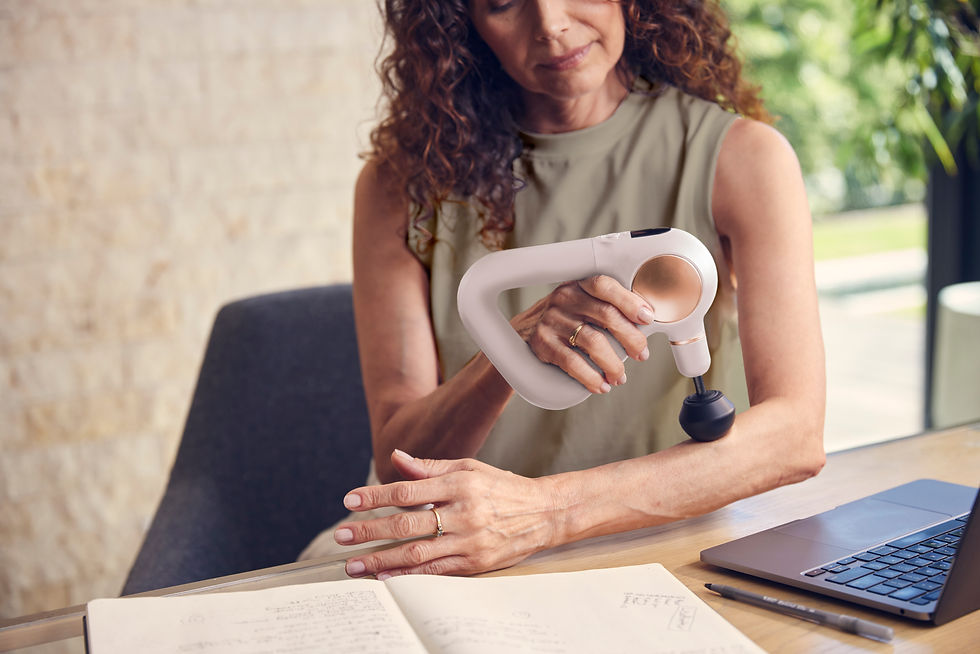 Thumbnail: Woman uses Theragun Sense on her arm while seated at office desk.