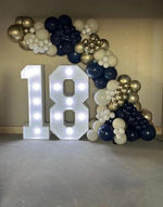 White LED number 18 display with navy, white and gold balloon garland for an 18th birthday celebration by The Cedars Events.
