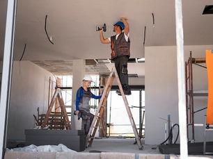 Two workers installing ceiling panels during home remodeling.