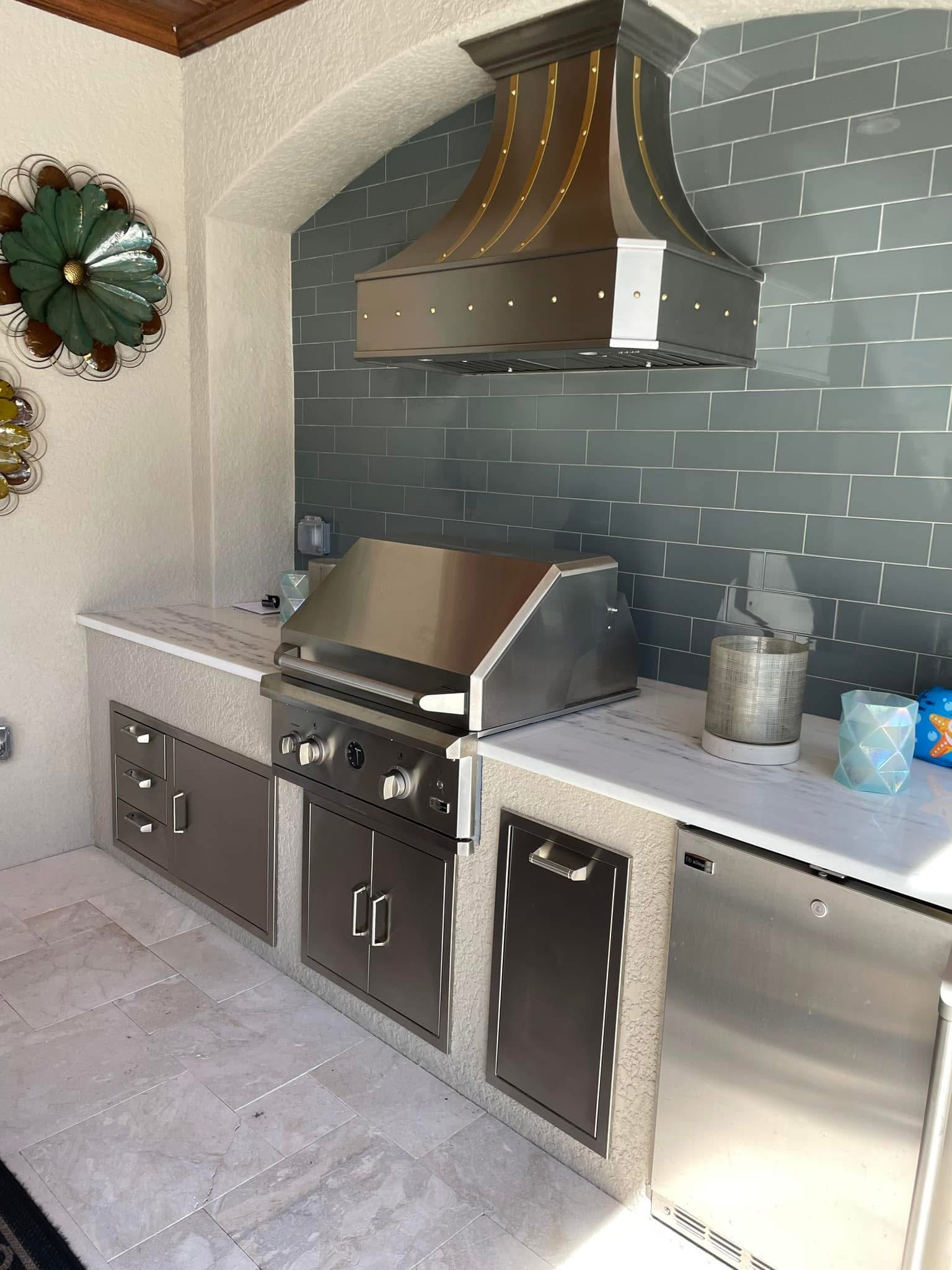 Outdoor kitchen with range hood, Naples area home by Coastal Custom Homes SWFL