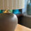 Thumbnail: Close -up Handmade table lamp with pale olive green and white stripes  lampshade on a taupe ceramic base.