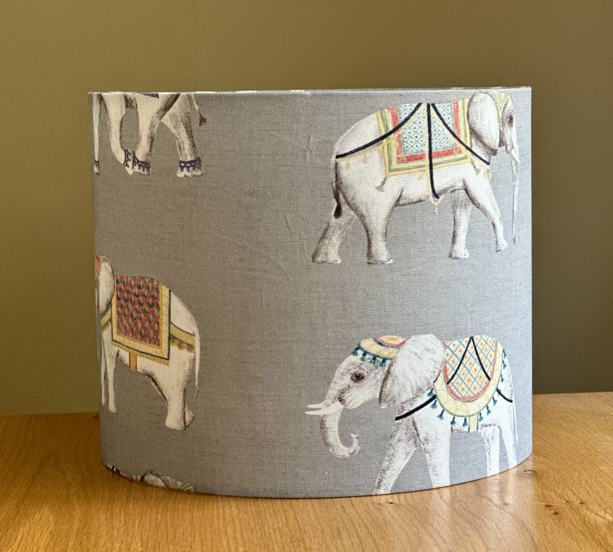 Grey fabric lampshade with illustrated decorative Elephant Parade wearing colorful patterned blankets