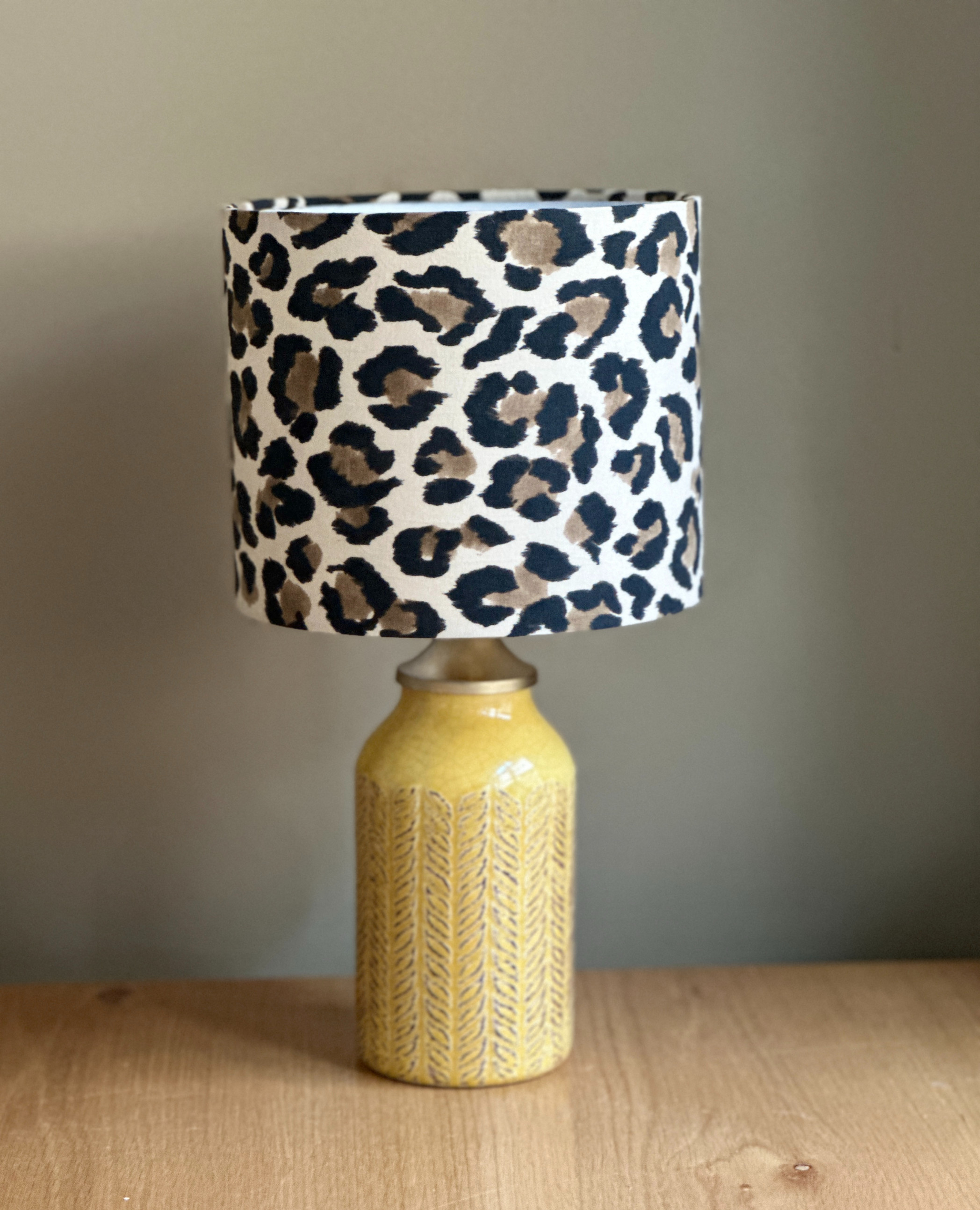 Mustard ceramic lamp base with carved leaf texture and a bold leopard fabric shade
