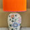 Thumbnail: A ceramic lamp base featuring an engraved floral pattern, inspired by Eastern motifs and a vivid orange silk shade