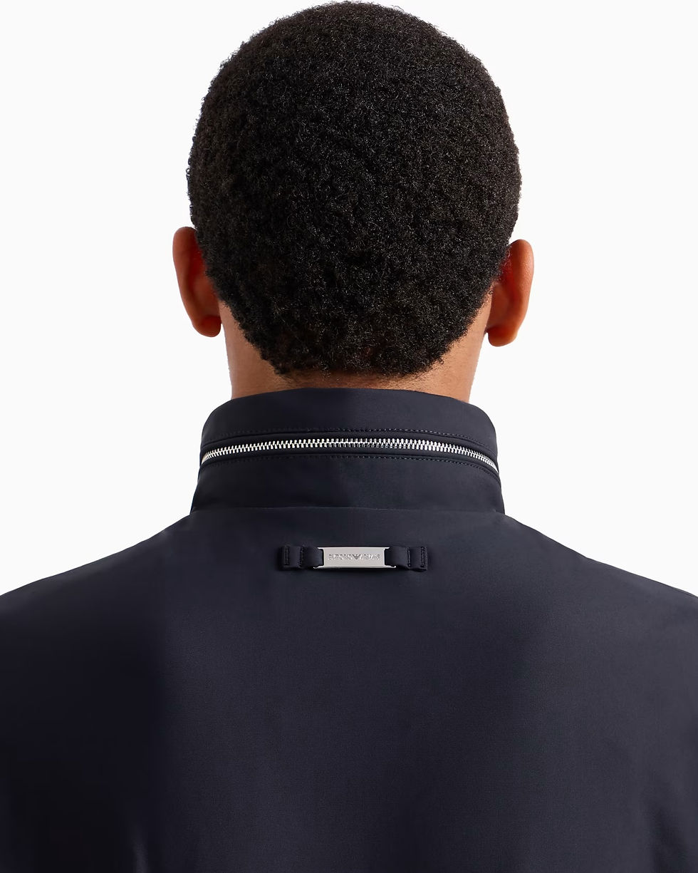 Miniature : Un homme porte un pull bleu marine. Col avec un détail argenté.