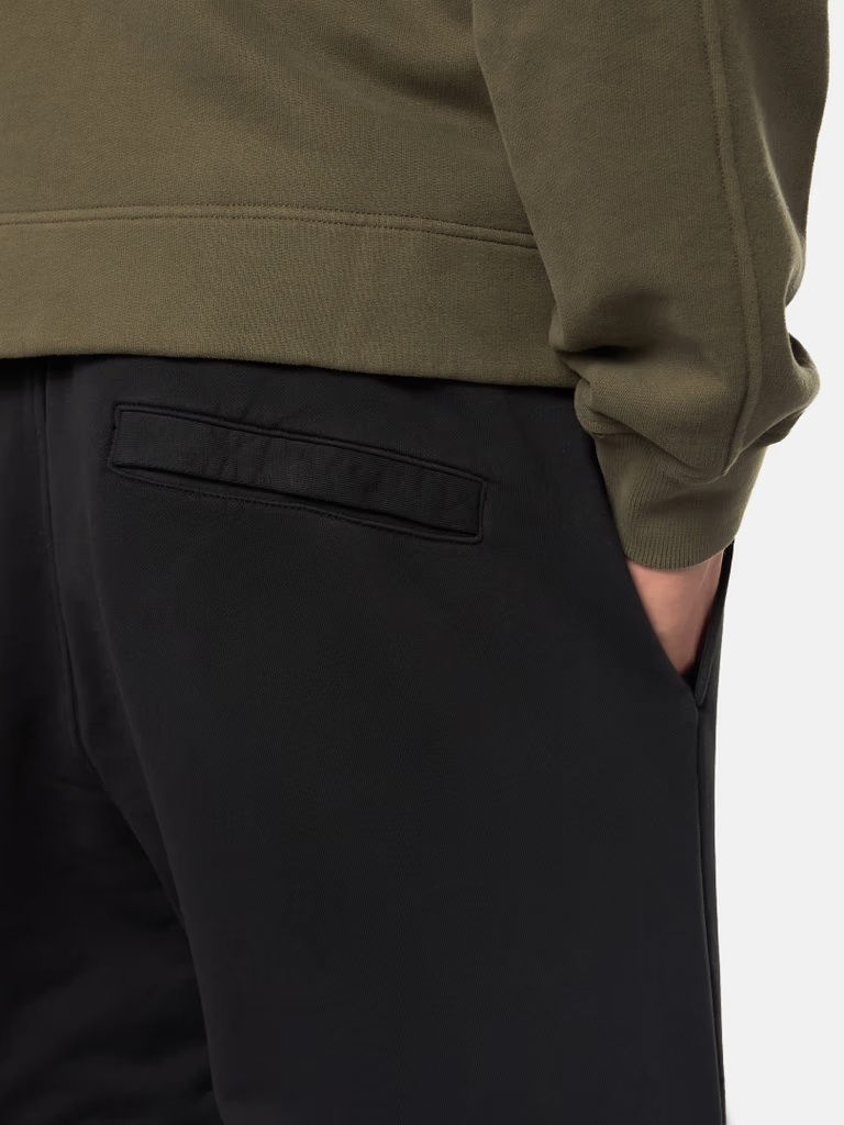 Miniature : Gros plan de pantalon noir et poche, en arrière plan un pull vert.