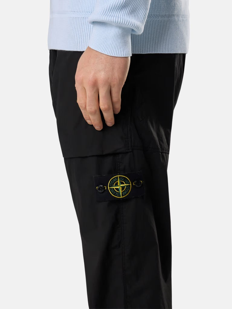 Miniature : Homme portant un pantalon noir avec le logo Stone Island visible. 2100039 60/2 COTTON JERSEY.