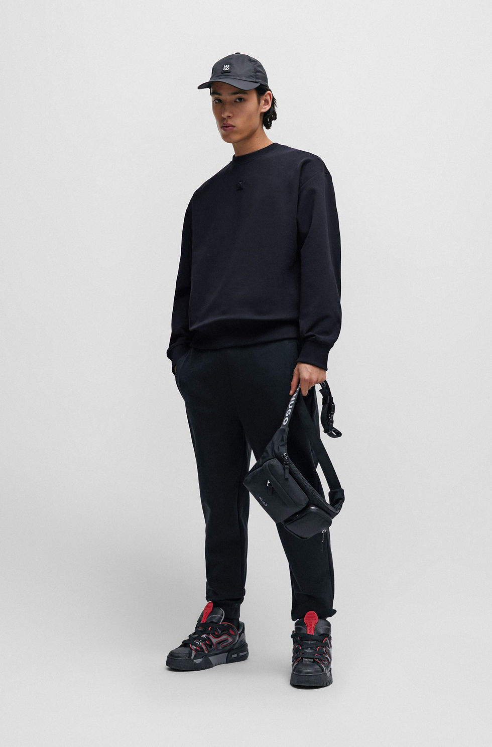 Homme en noir avec sac bandoulière. Tenue décontractée. Boutique Karsenty.