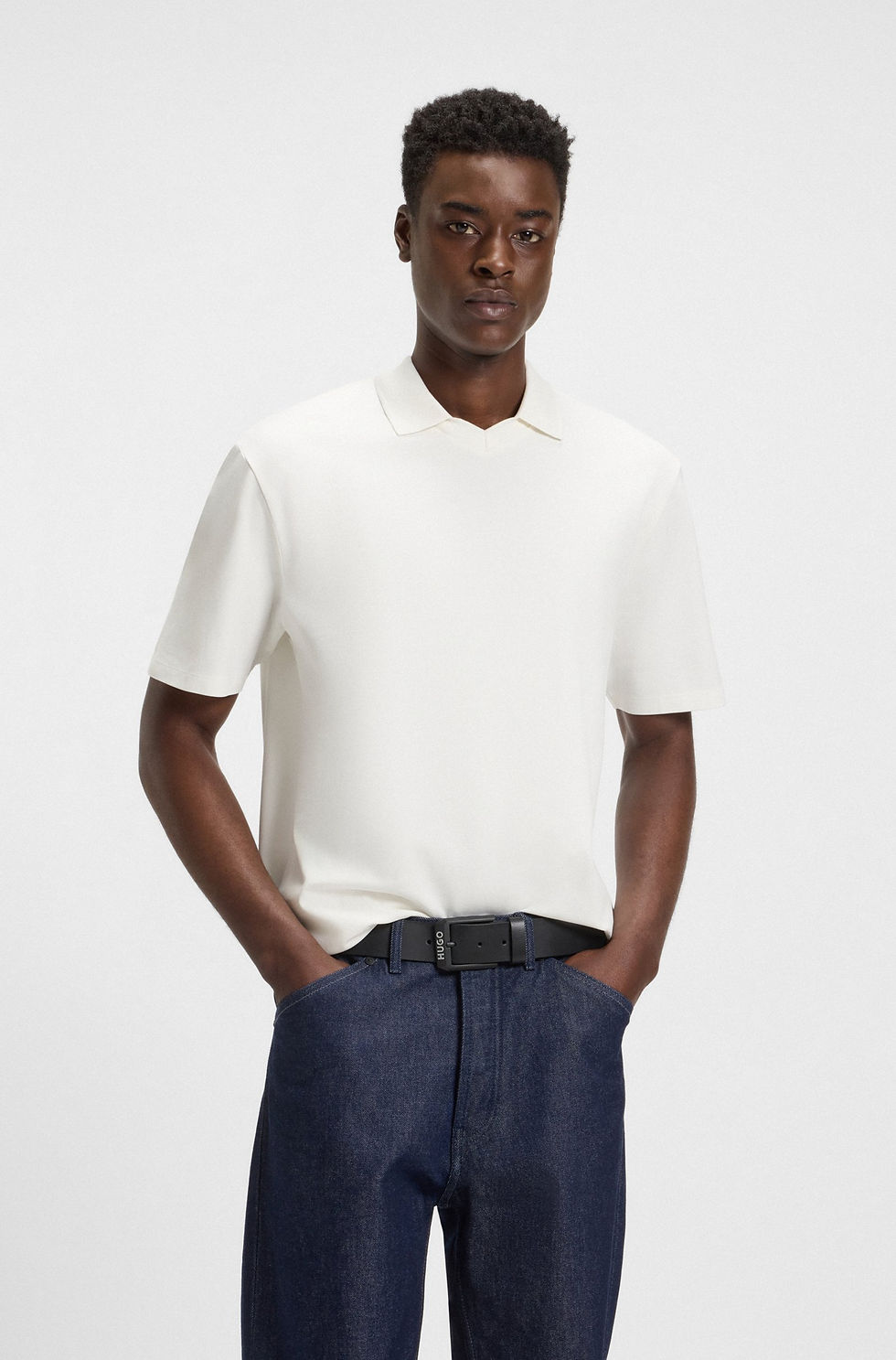 Man in cream polo shirt. T-shirt slim en coton mercerisé. Dark pants and belt.