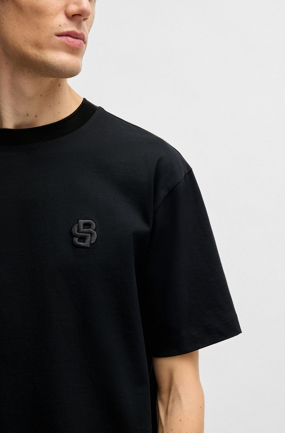 Miniature : Homme portant un t-shirt noir avec logo. Boutique Karsenty.
