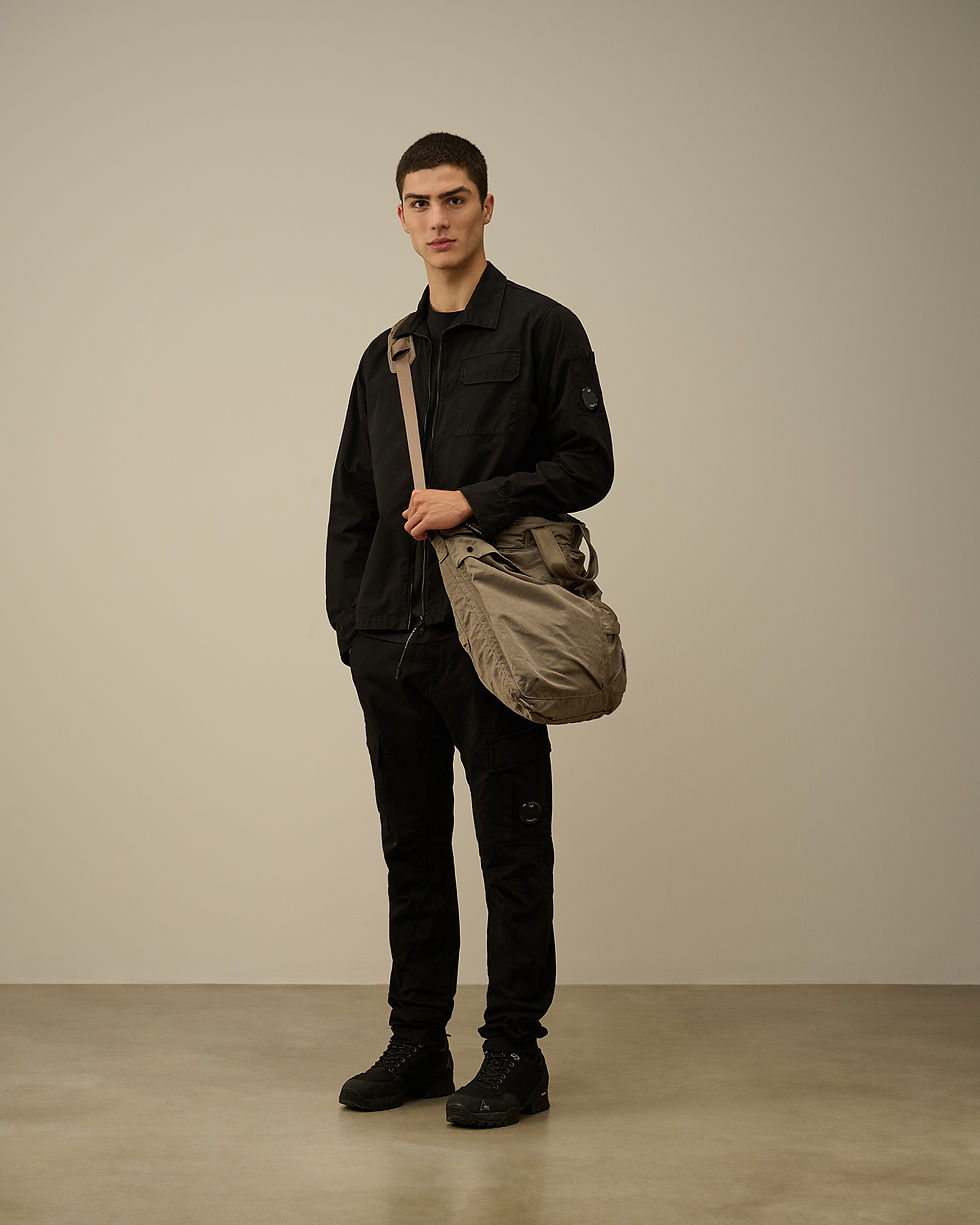 Miniature : Un homme avec un sac, Boutique Karsenty, portant des vêtements noirs, avec un arrière-plan neutre.