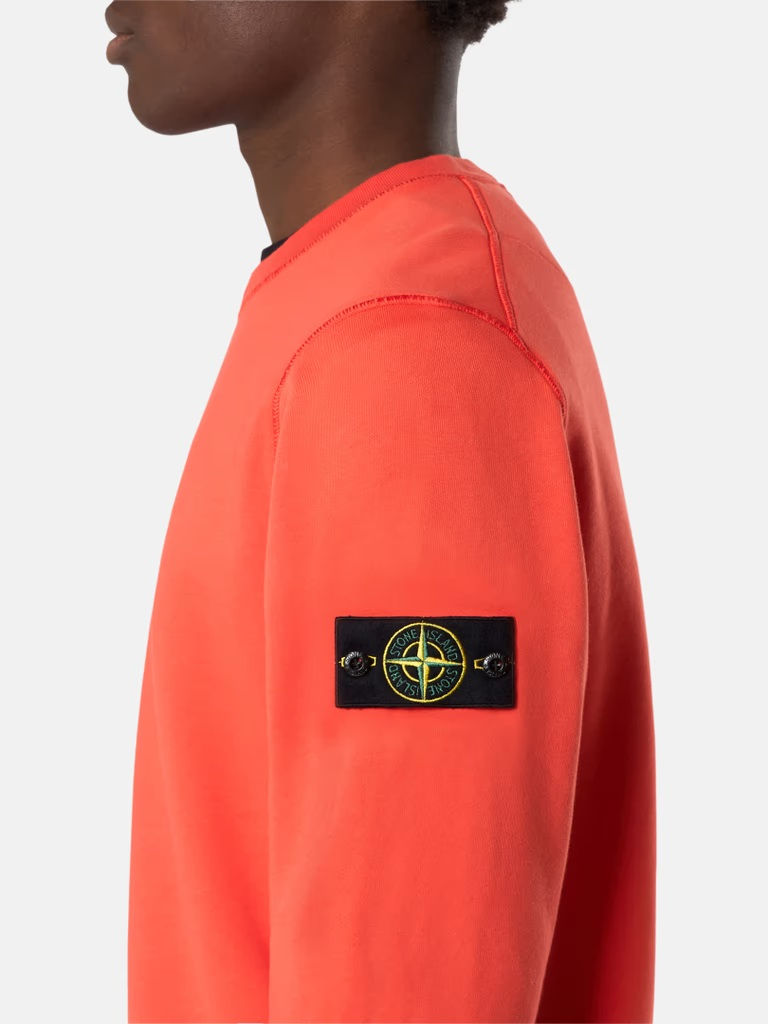 Miniature : Homme portant un pull orange avec le logo Stone Island sur la manche.