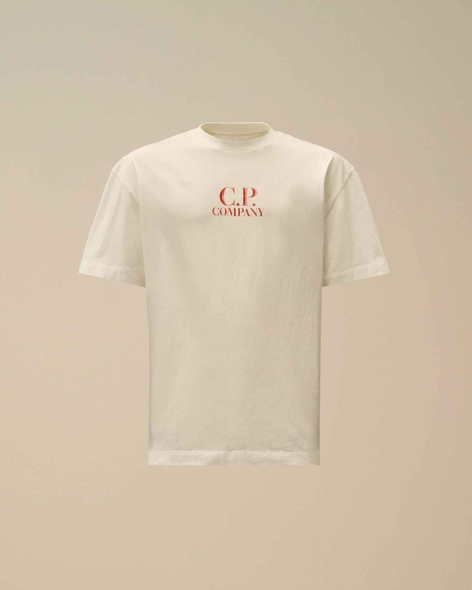 T-shirt beige avec texte rouge "C.P. Company" sur fond clair.