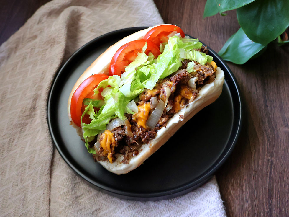 Vegan chopped cheese sandwich with shredded lettuce and sliced tomatoes served on a hoagie bun.