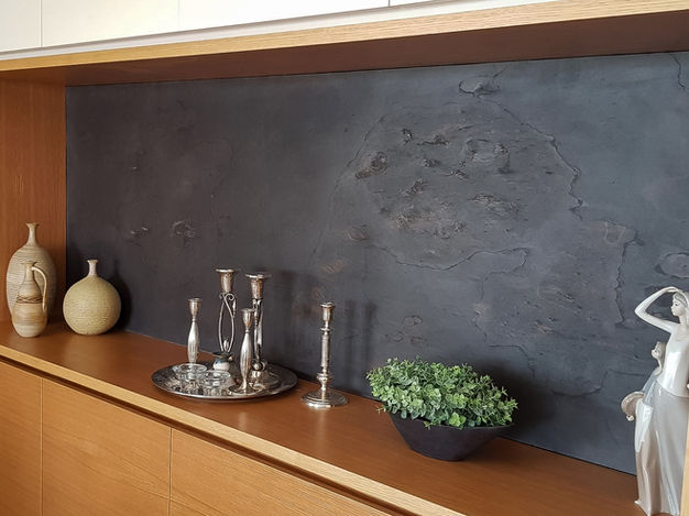 A wooden shelf with vases, candlesticks, and plants against a dark wall. The back panel is a very thin, self-adhesive natural stone foil with real slate.