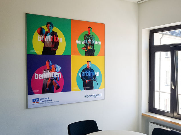 Buntes Volksbank Poster mit den Wörtern: bewirken, voranschreiten, berühren, verbinden, #bewegend.