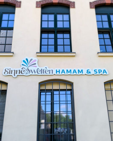 Business sign SinneSWELTEN HAMAM & SPA on building.