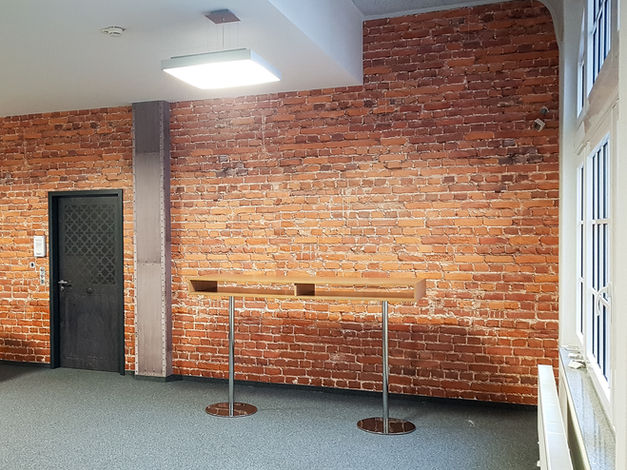 Ziegelwand in einem Raum mit dunkler Tür, Fenster und Holzständer.