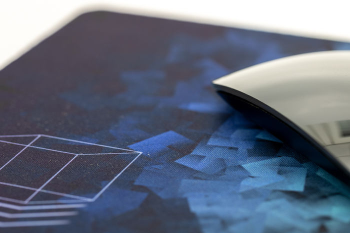 Mousepad mit angeschnittener schwarzer Magicmouse und würfelartigem design in blau