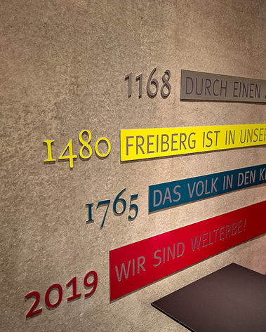 An einer Betonwand sind einzelbuchstaben und schilder in verschiedenen farben von uns montiert wurden.