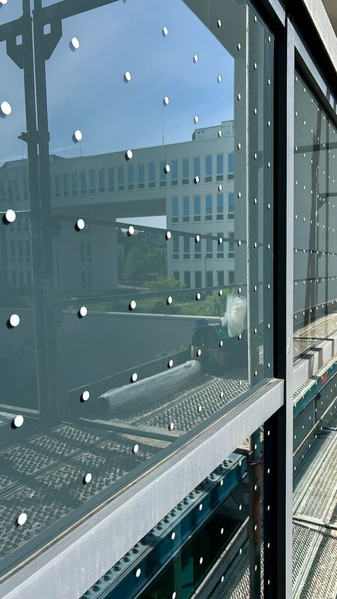 Moderne Glasfassade, reflektierende Punkte, Technische Folierung, spiegelt Gebäude und Himmel. Birdsafe Vogeslschlag Schutzfolie